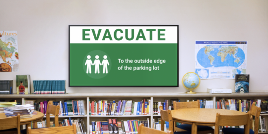 A school library with emergency alert displayed on screen.